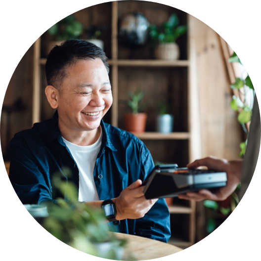 Senior Asian man paying bill with credit card contactless payment on smartphone in a cafe